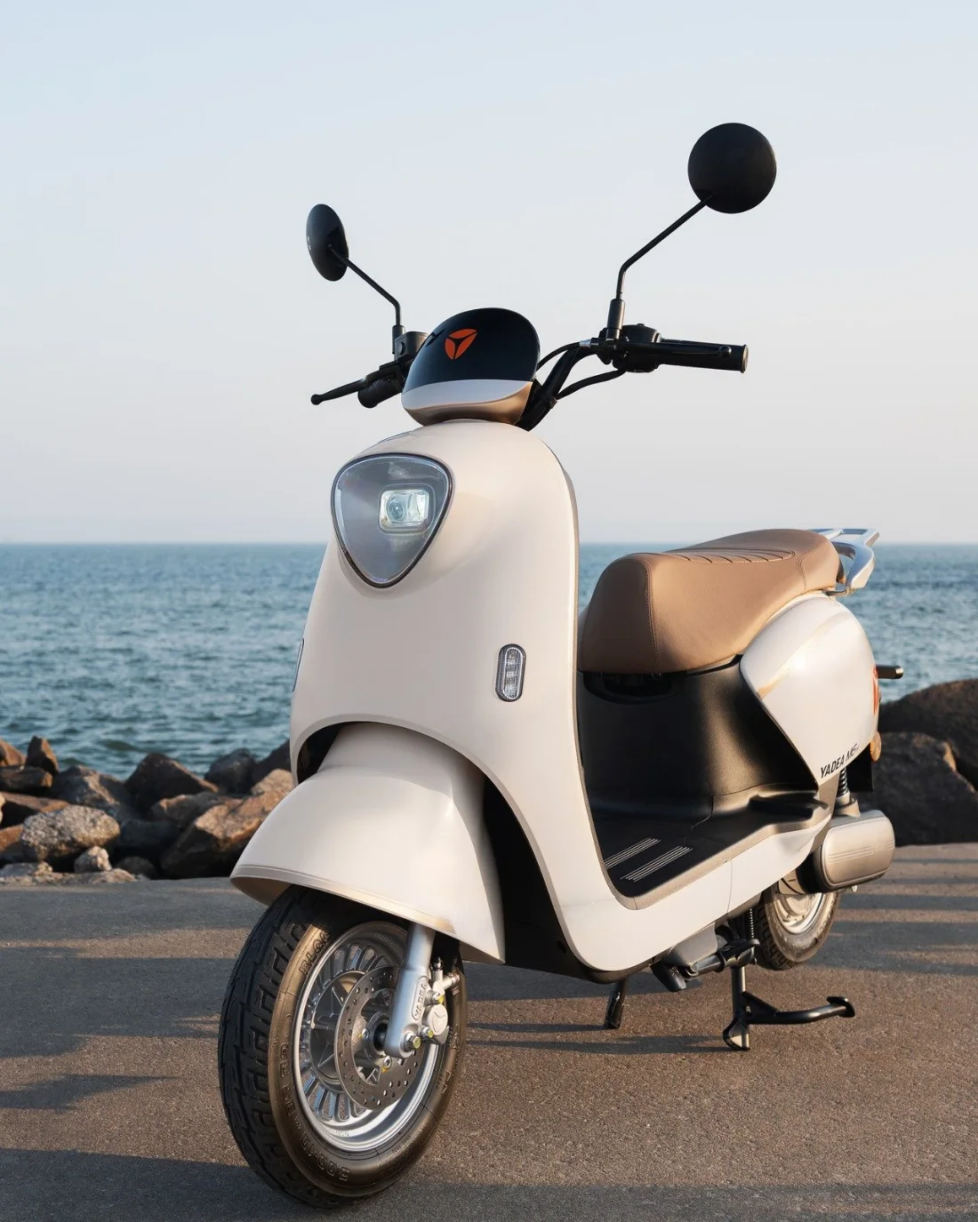 Scooter elétrica Yadea M6 estacionada na orla, com o mar ao fundo